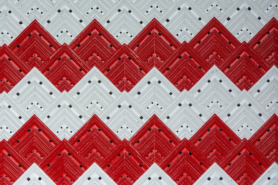 Decorative red and white zigzag pattern with geometric tiles creating a bold visual design.